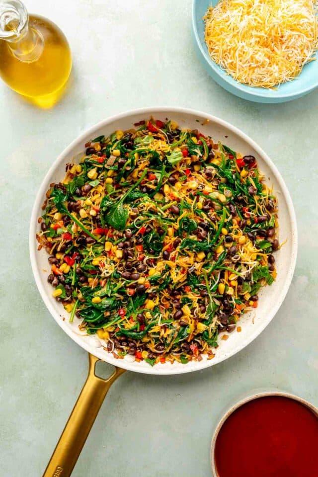 Mixing and cooking spinach with cheese, black beans and corn.