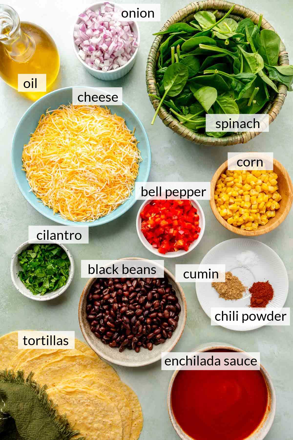 Small bowls filled with spinach, cheese, beans, corn, chopped onion, enchilada sauce and spices.