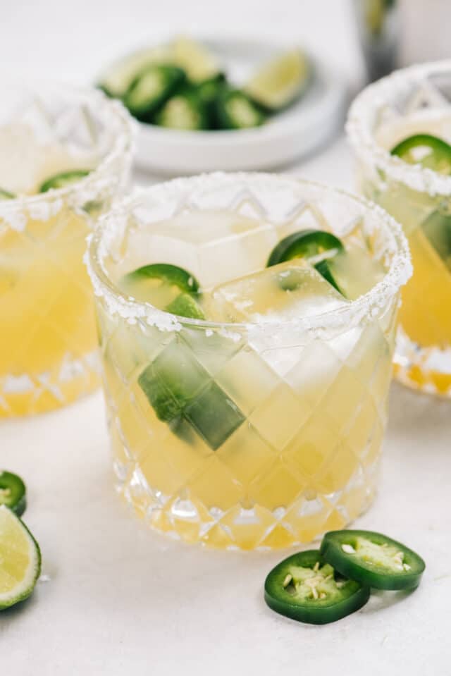 jalapeño margarita in a glass with salt on the rim and jalapeño slices
