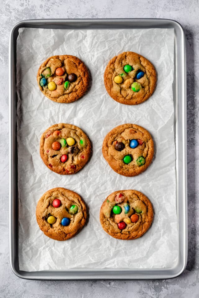 M&M cookies baked on a parchment lined cookie sheet pan