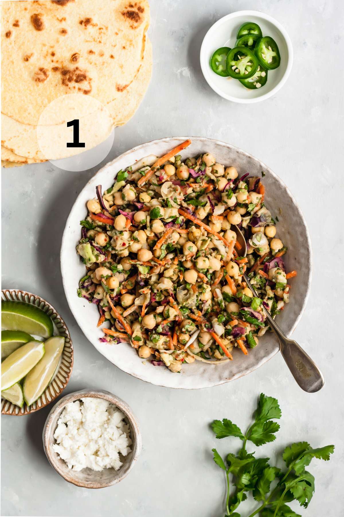 Stirring chickpeas with mashed avocado and slaw in a white bowl.