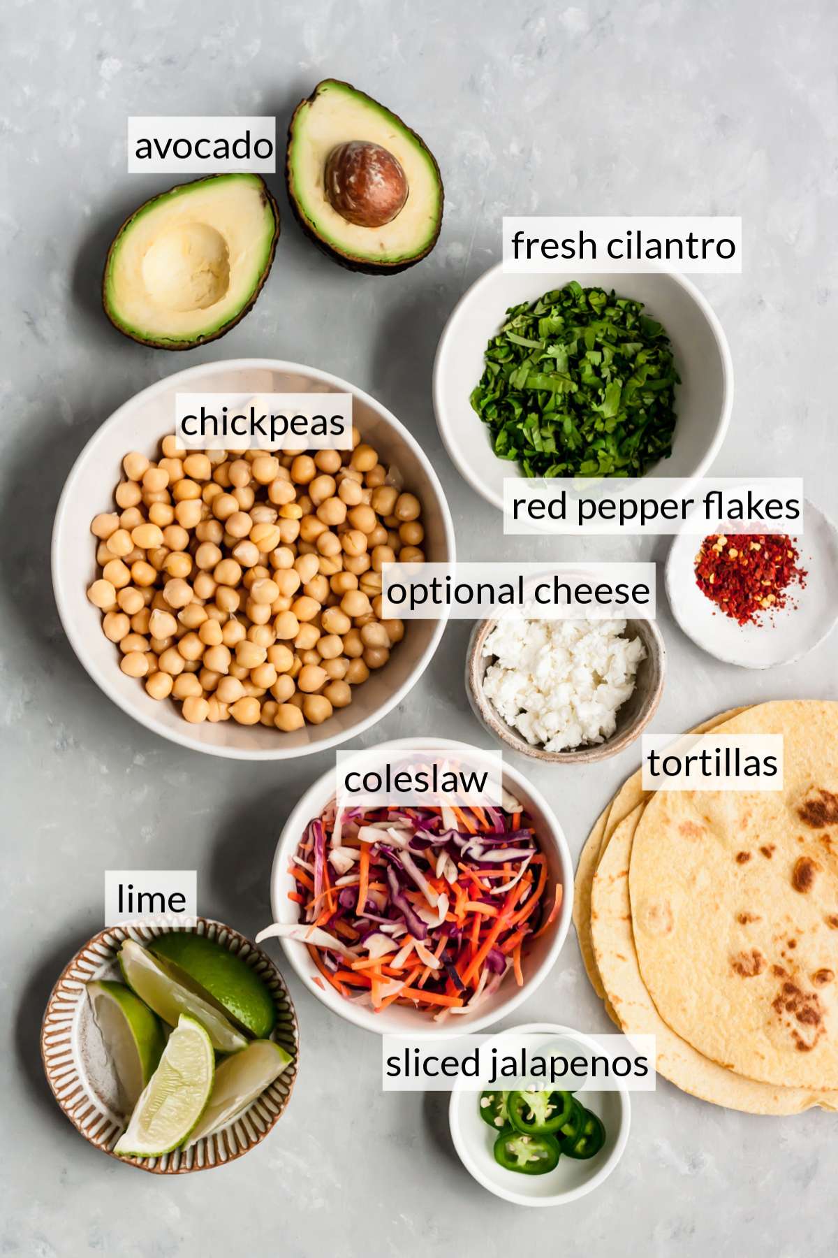 Small bowls with chickpeas, coleslaw, cheese, cilantro and sliced jalapeño.