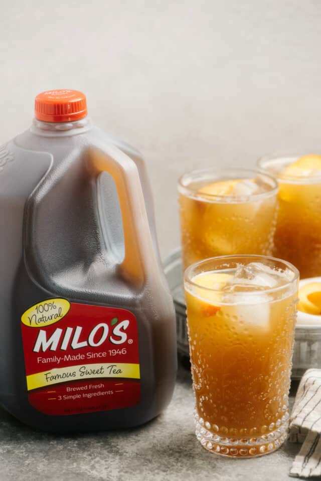 peach cocktail near a jug of Milo's sweet tea