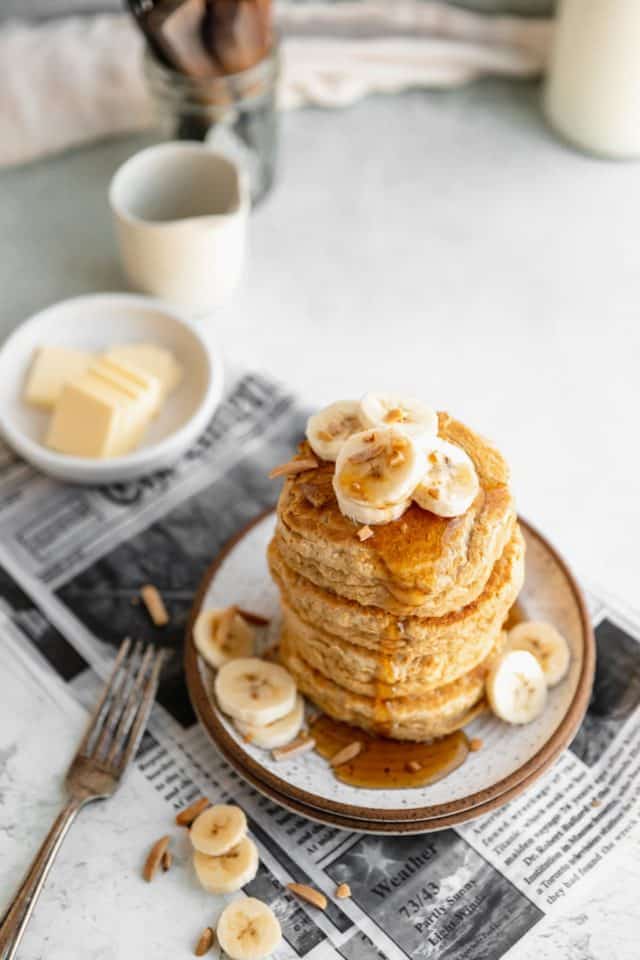 fluffy whole wheat pancakes topped with banana slices and maple syrup