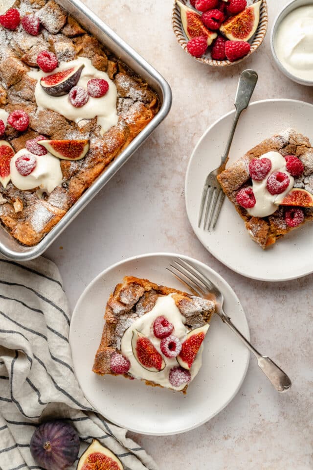 French toast casserole served on small white plates and topped with fresh figs and raspberries