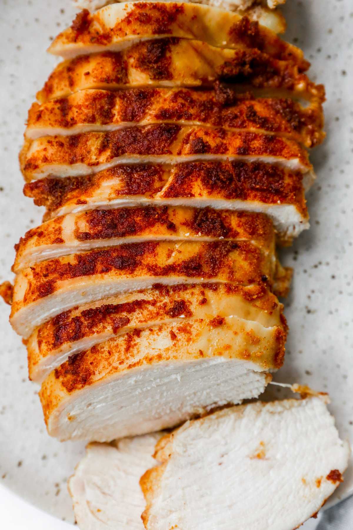 Sliced, seasoned baked chicken on a white plate.