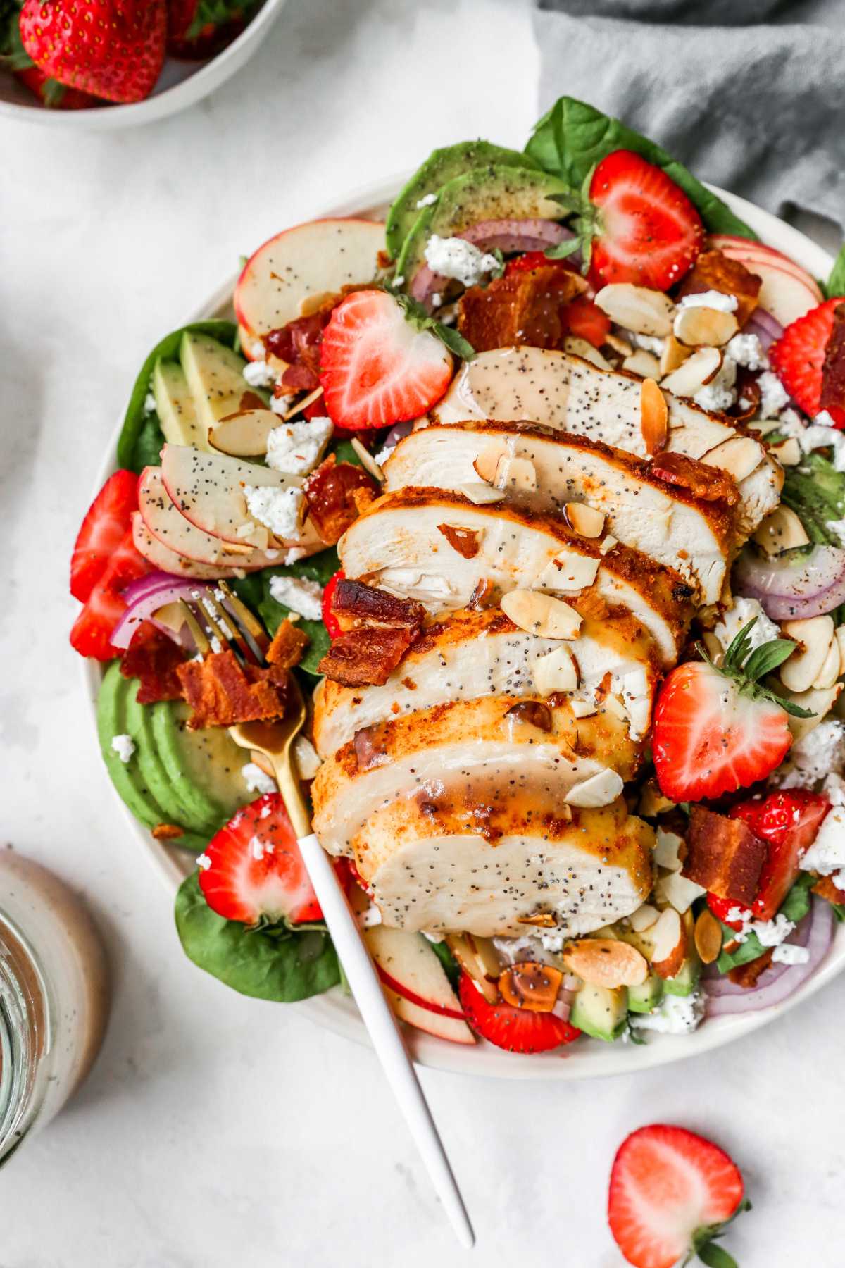Spinach salad topped with strawberries and chicken.