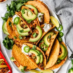 crispy beef tacos topped with avocado slices and sour cream