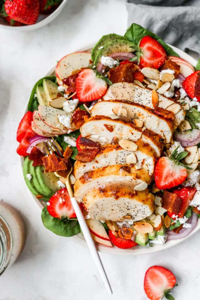 sliced chicken breast in a salad with strawberries and avocado