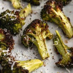 roasted broccoli on a baking sheet topped with parmesan cheese