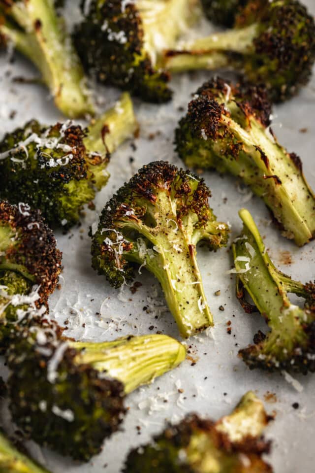 roasted broccoli on a baking sheet topped with parmesan cheese