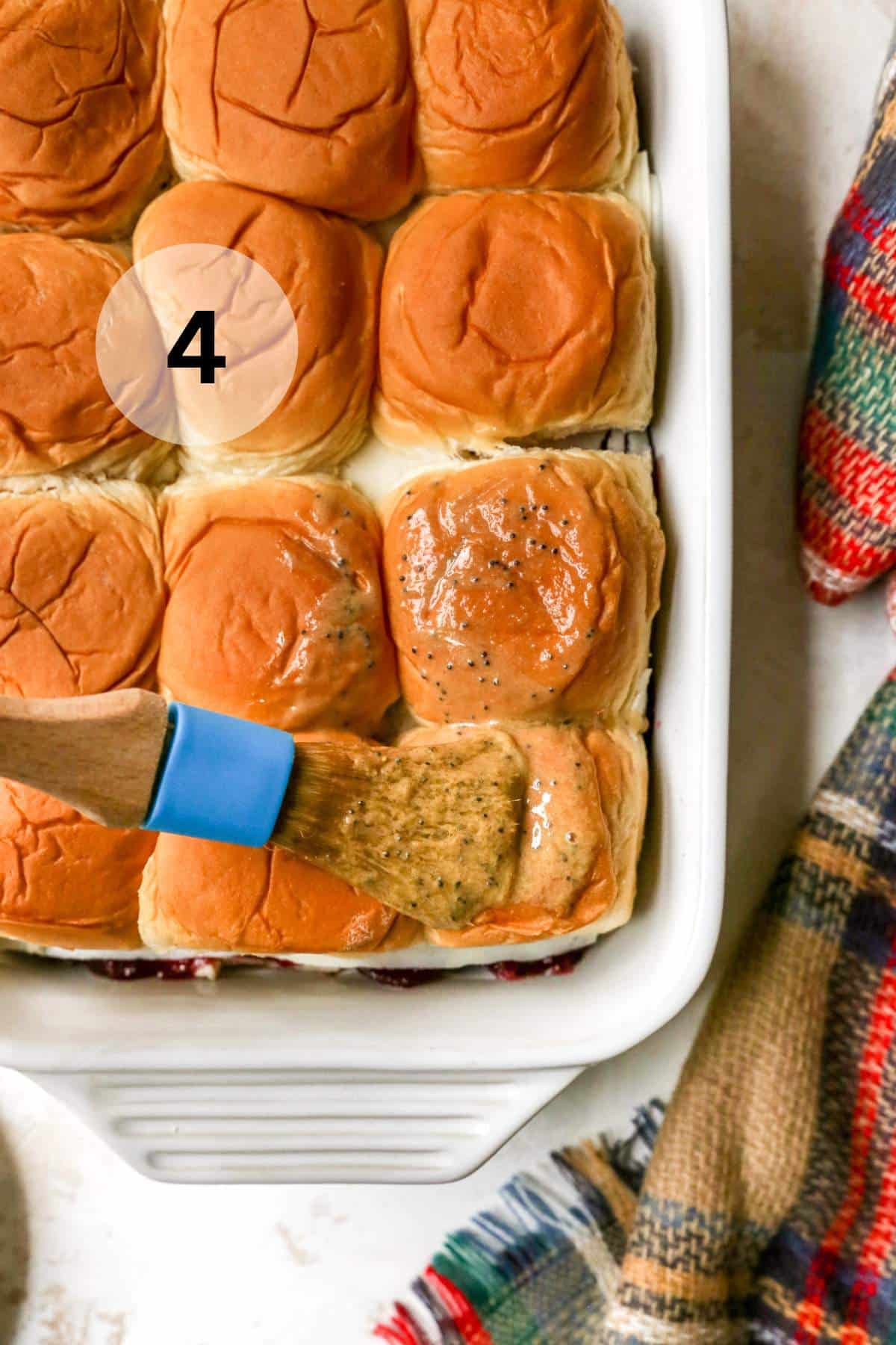 Brushing the tops of Hawaiian rolls with melted butter.