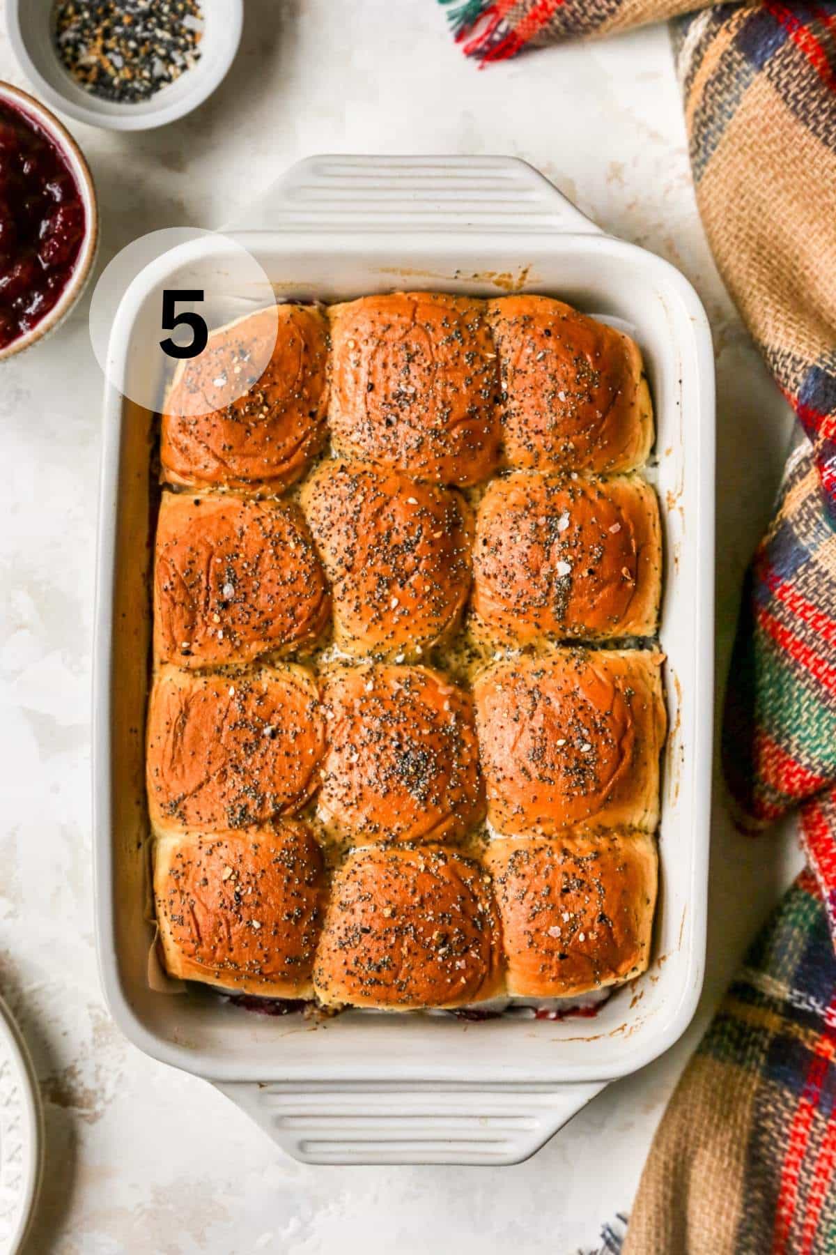 Baked turkey cranberry sliders in a white casserole dish.
