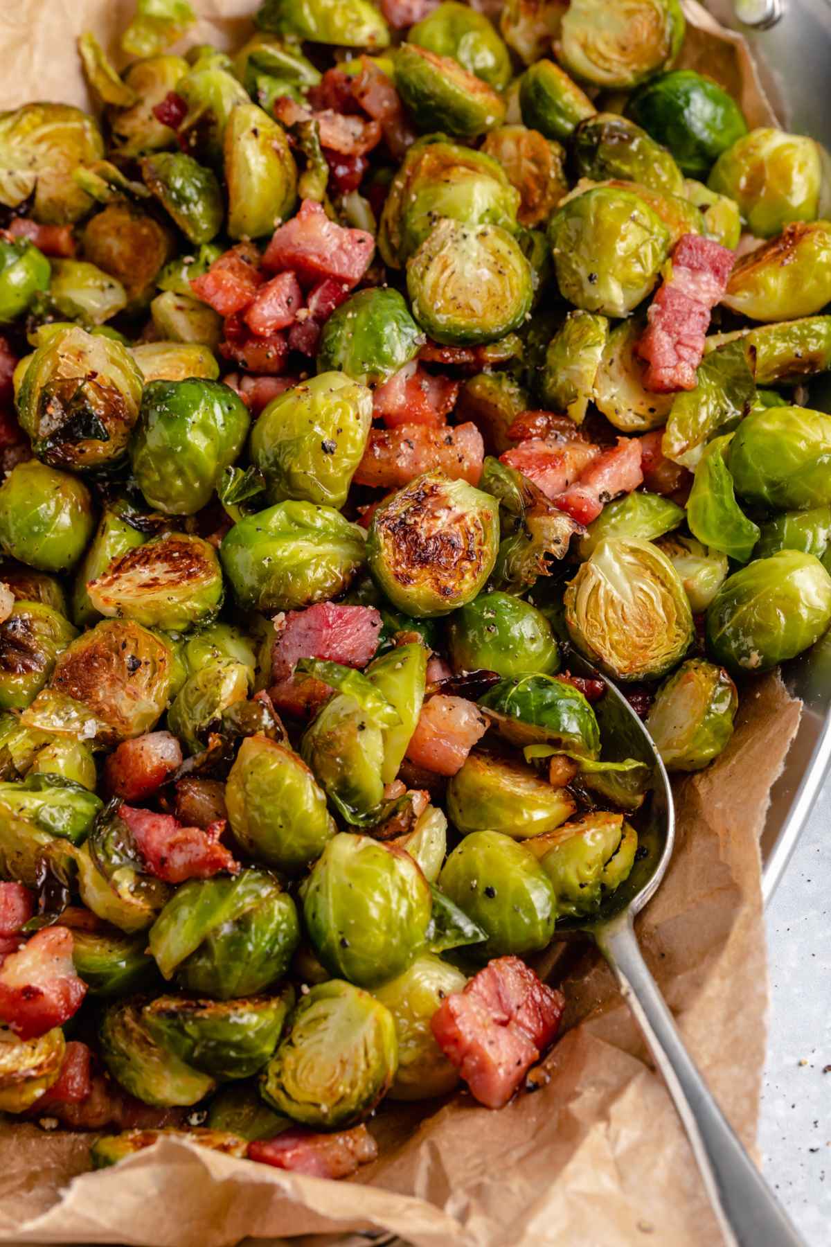 Serving bacon roasted Brussels sprouts with a large spoon.