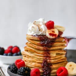 banana pancakes stacked on a plate and topped with berries