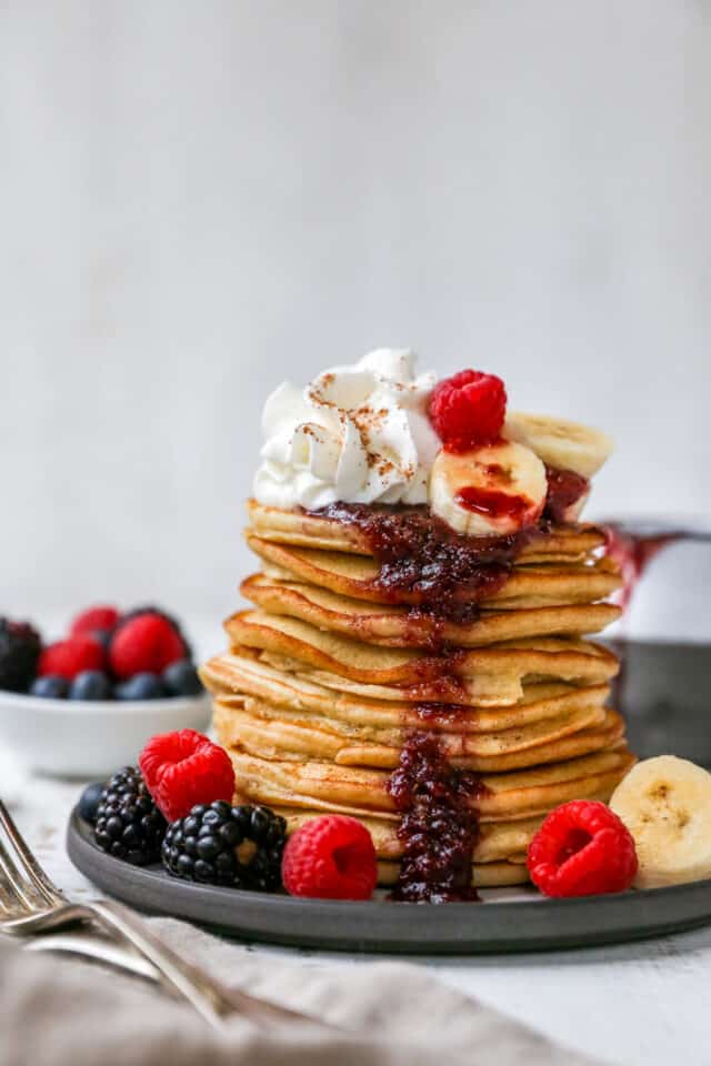 banana pancakes stacked on a plate and topped with berries 