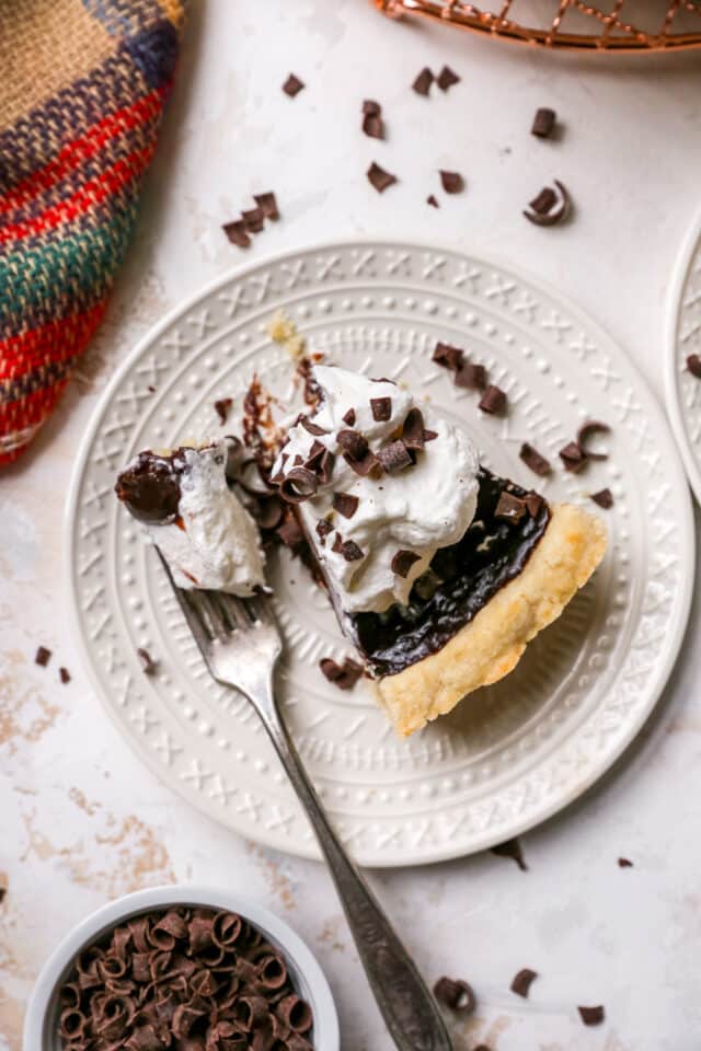 using a fork to eat a chocolate pie topped with whipped cream