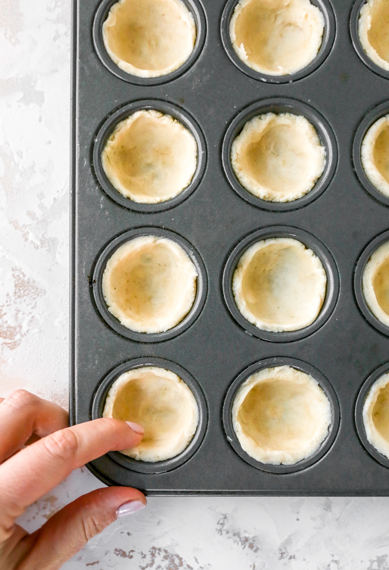pressing crust into a mini muffin pan