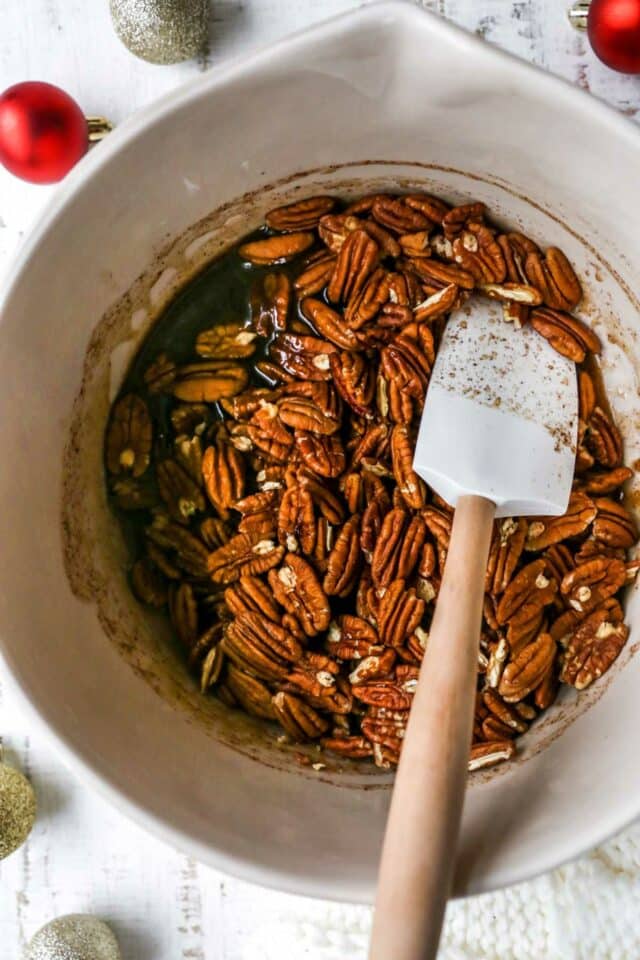Stirring pecan halves with melted butter mixture.