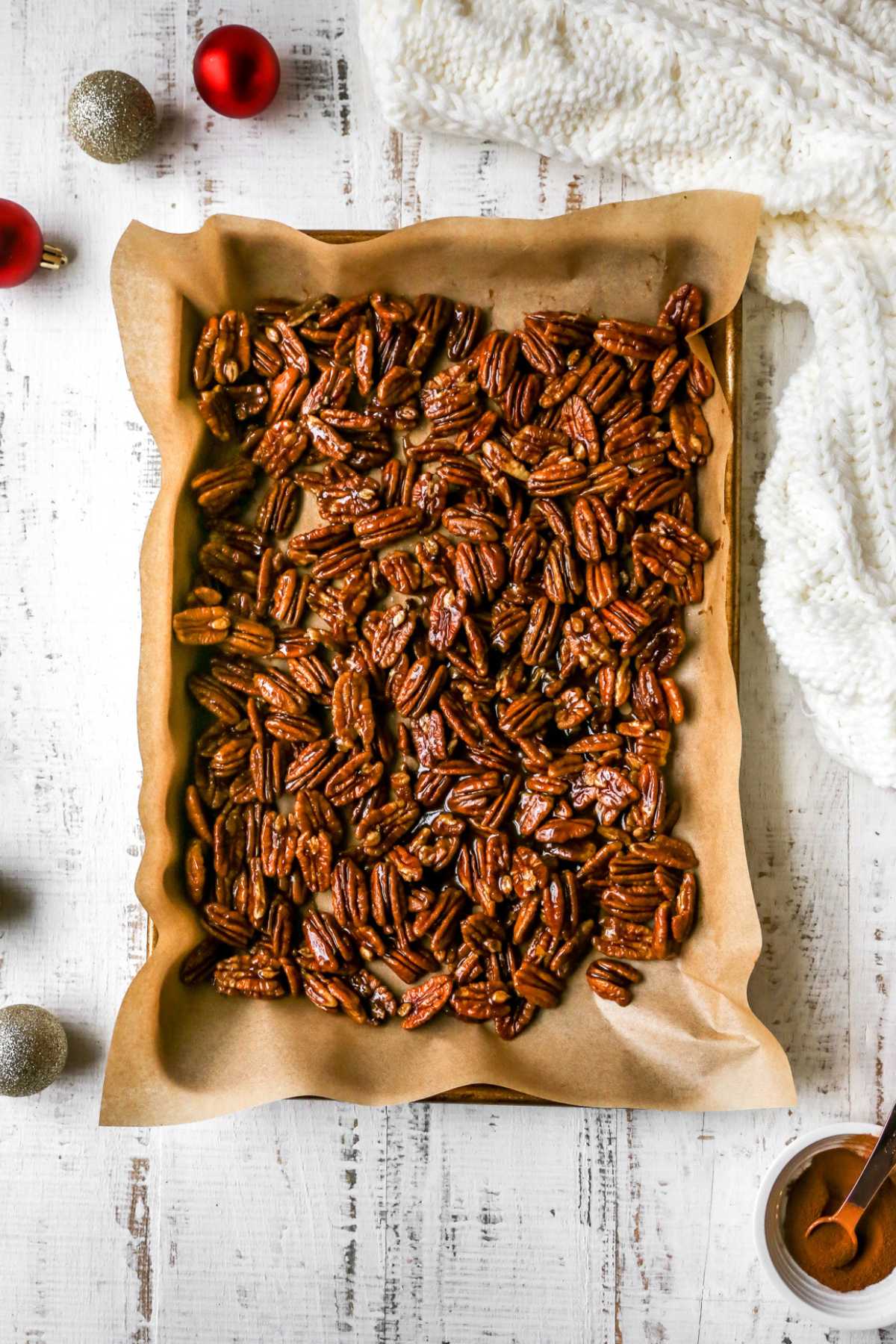 Candied pecans cooling on a pan lined with parchment paper.