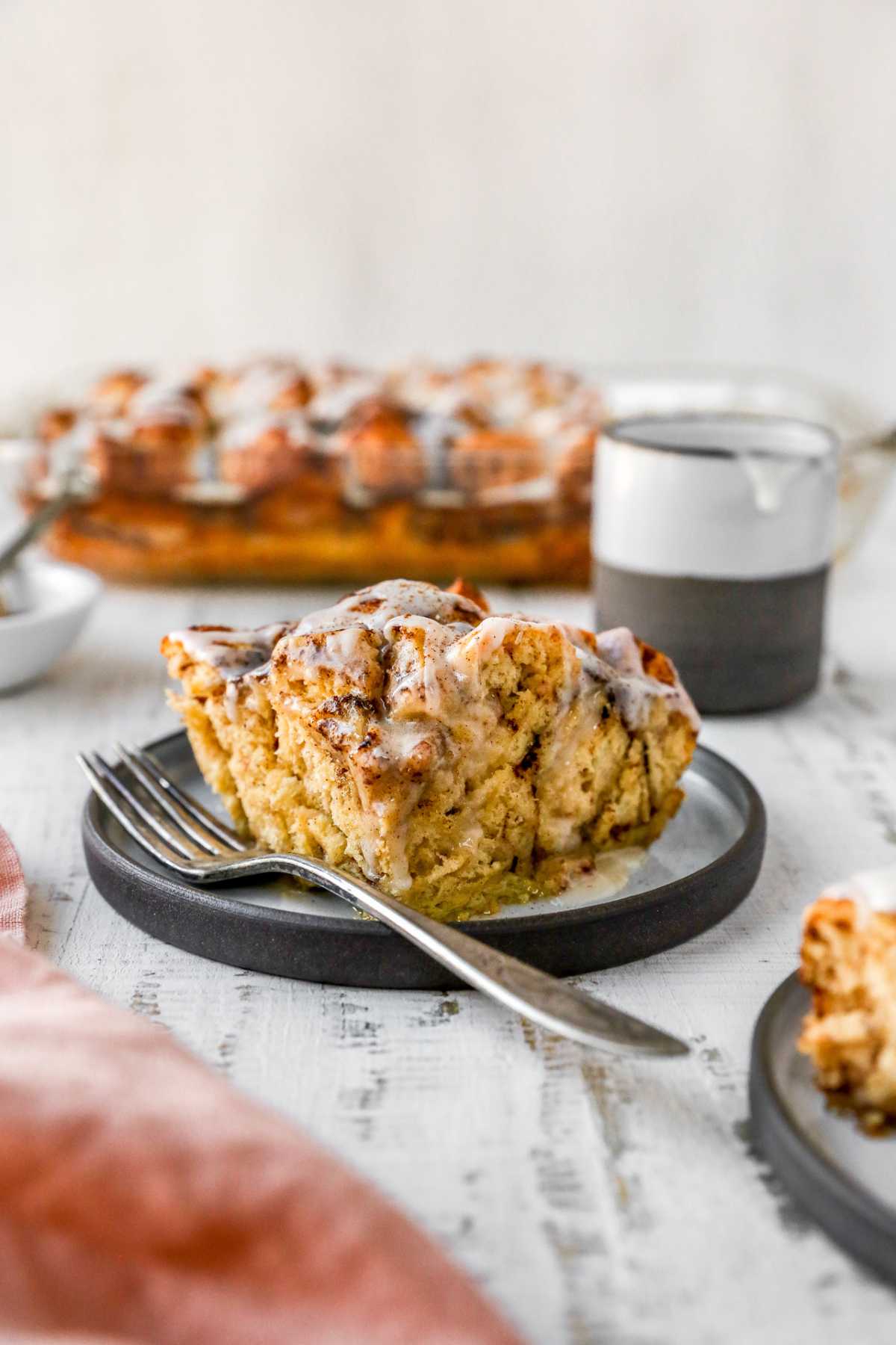 Piece of cinnamon roll casserole on a plate with a fork.