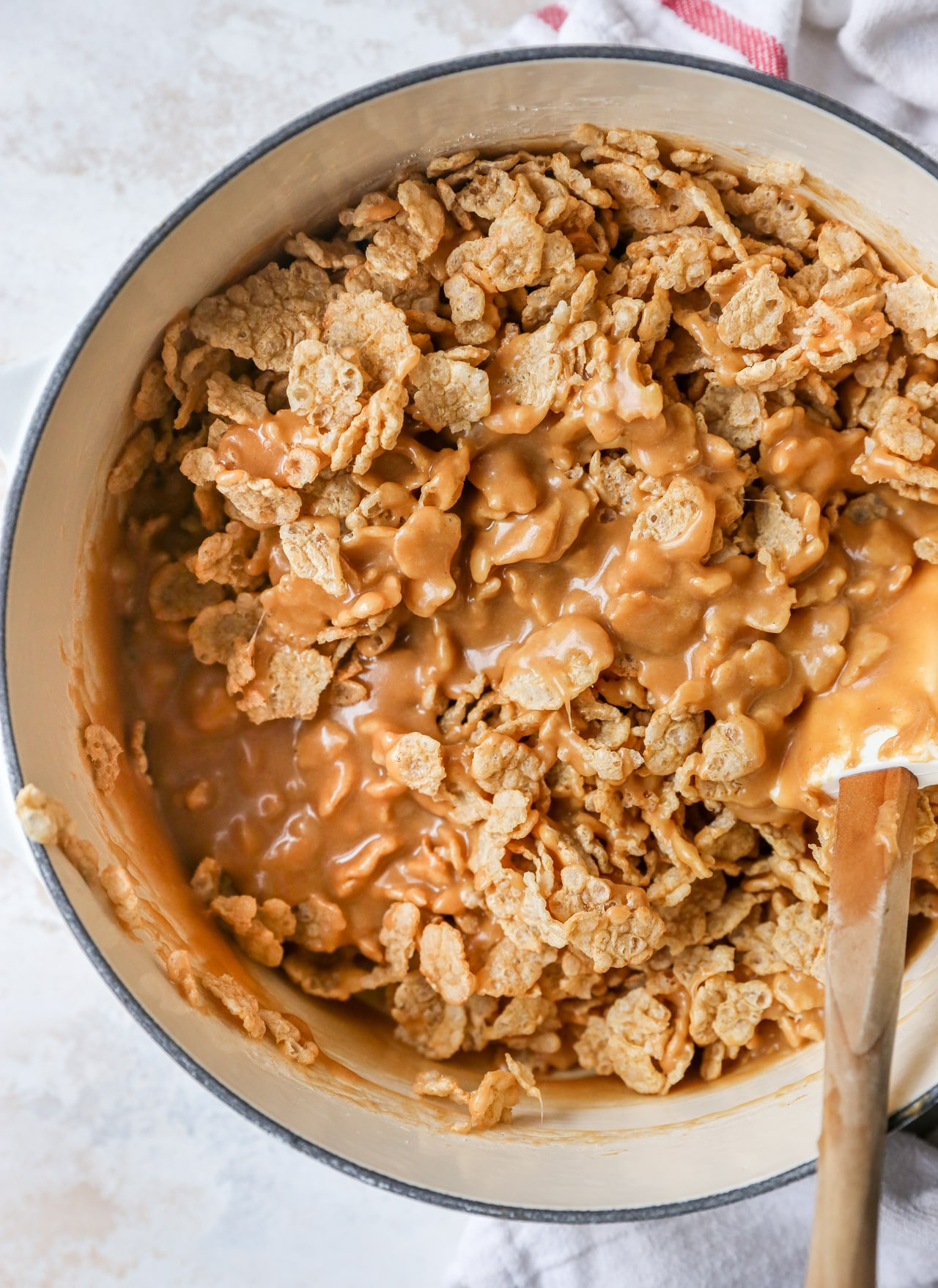 Stirring cornflakes and peanut butter together.
