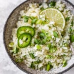 cilantro lime cauliflower rice garnished with fresh cilantro, sliced jalapeño and a lime wedge