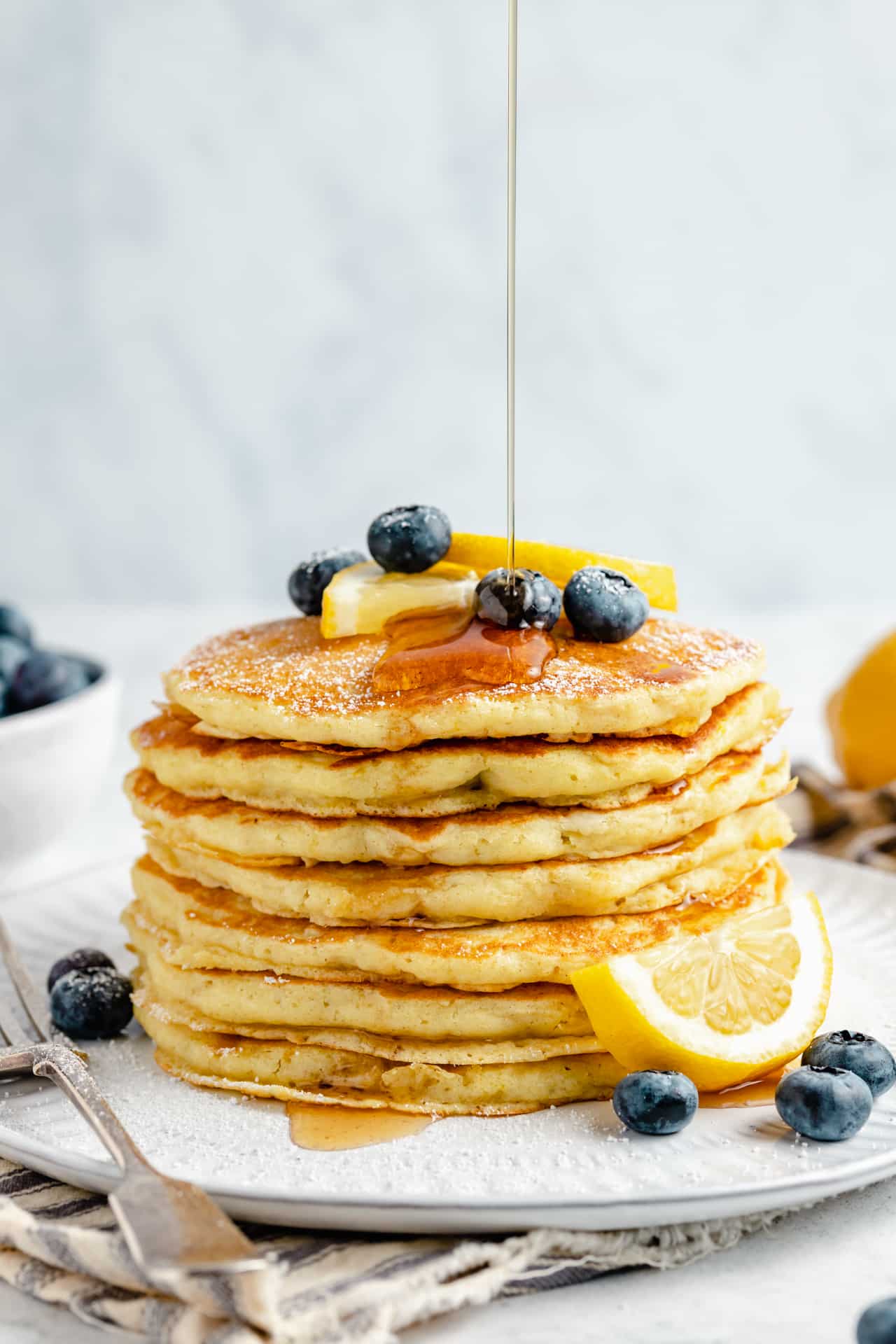 pouring syrup over stack of pancakes