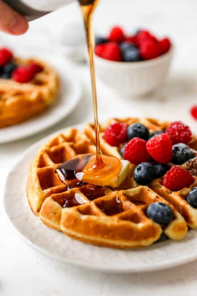 drizzling maple syrup over a buttermilk waffle