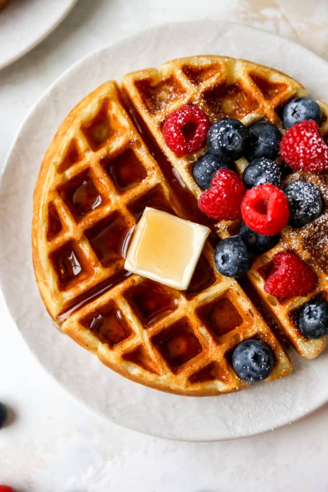 fluffy waffle topped with butter, syrup and fruit