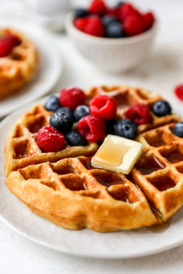 Belgian waffle with a pat of butter, syrup and berries