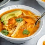 Healthy chicken tortilla soup topped with tortilla strips, avocado and fresh cilantro.