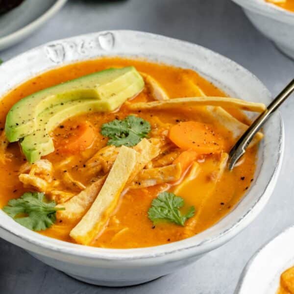 Healthy chicken tortilla soup topped with tortilla strips, avocado and fresh cilantro.
