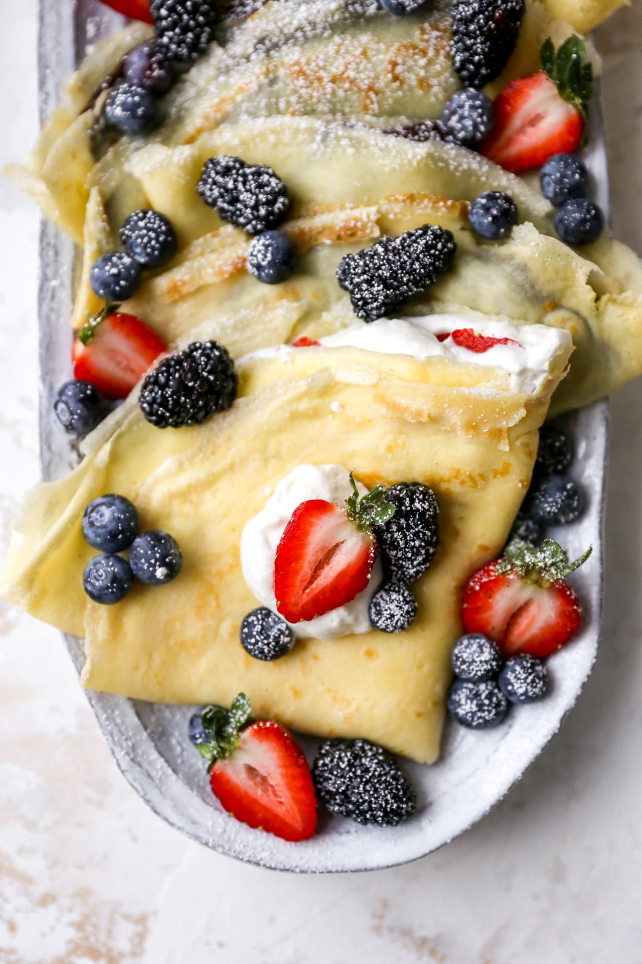 folded crepes topped with whipped cream and blueberries