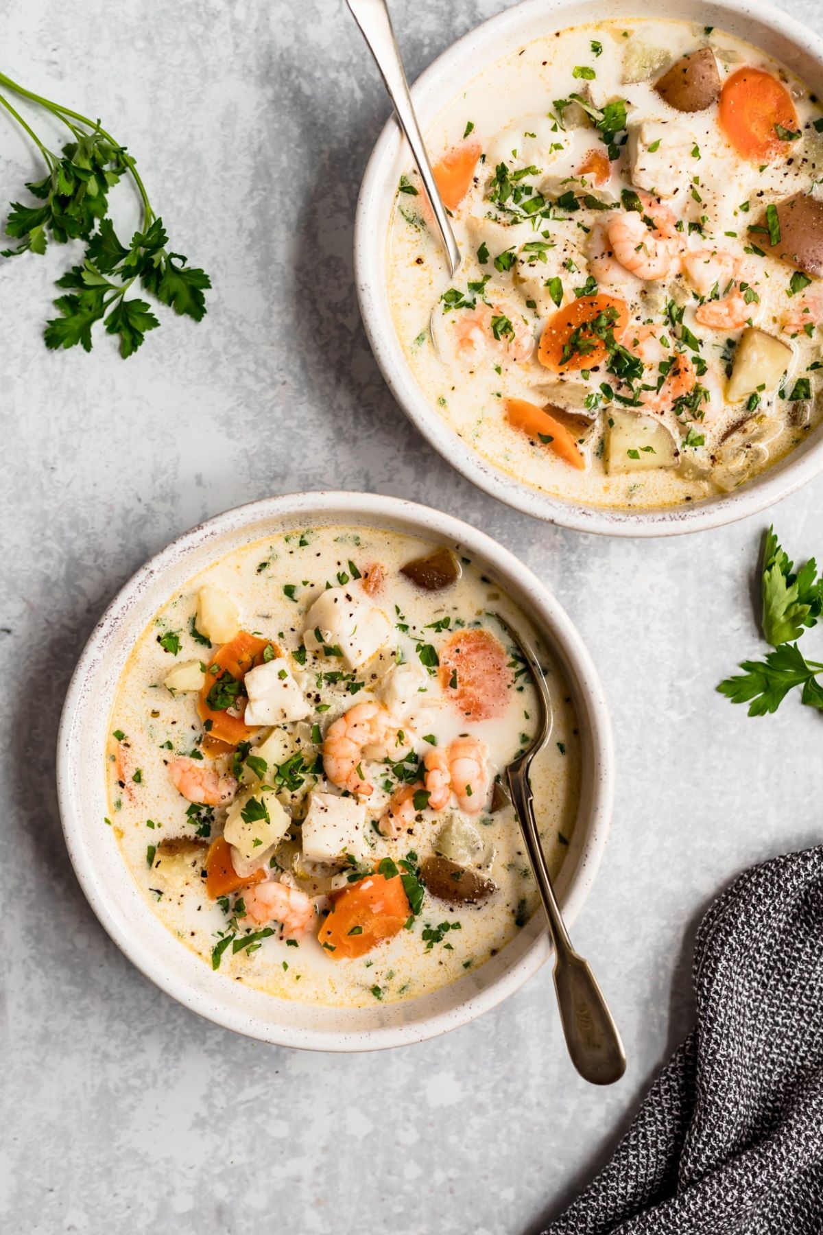 Soup with shrimp, fish, potatoes and carrots in white bowls.