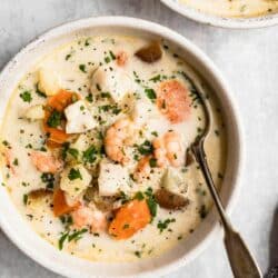 Seafood chowder in a white bowl with a spoon.