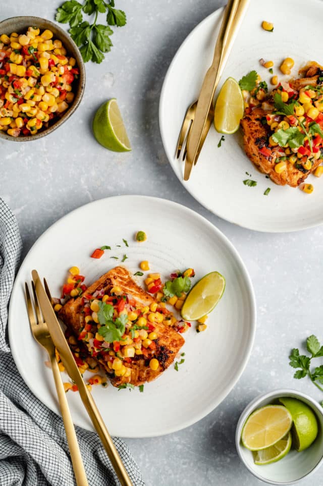 Plates of pan fried cod topped with corn salsa.