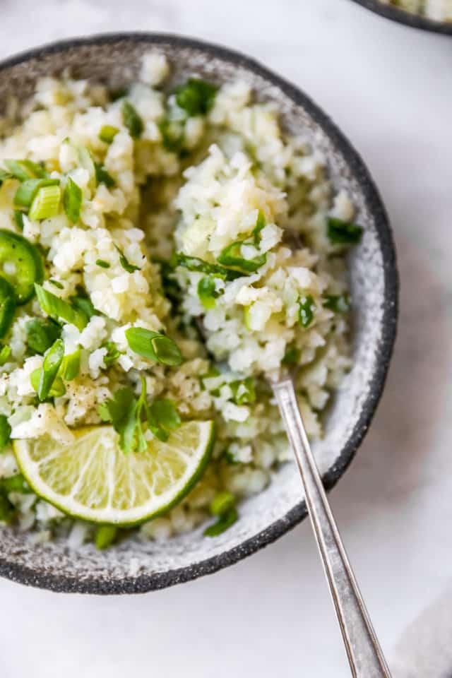 cauliflower rice garnished with fresh cilantro and served with a spoon
