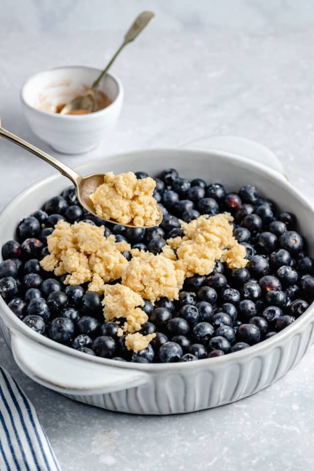 adding the biscuit-like topping over blueberries 