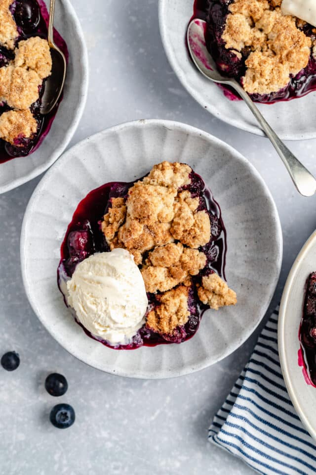 bowl of blueberry cobbler topped with vanilla ice cream