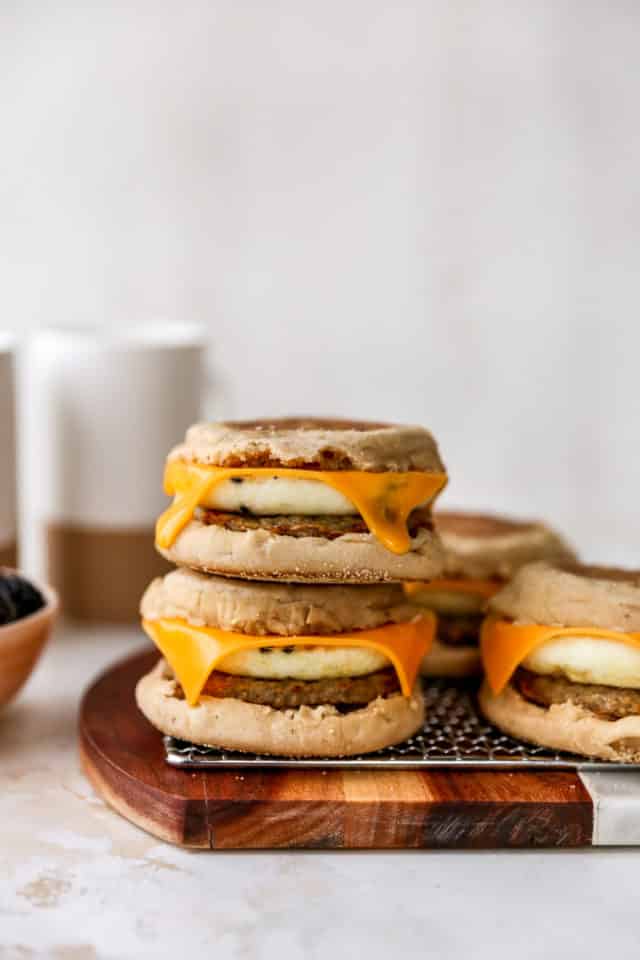 stacked breakfast sandwiches made with sausage, egg and cheese on an English muffin