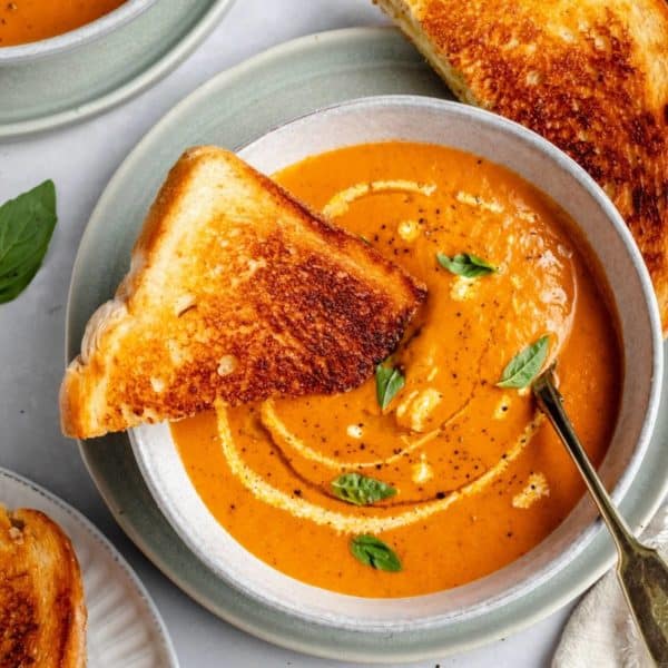 grilled cheese dipped into a bowl of roasted tomato soup