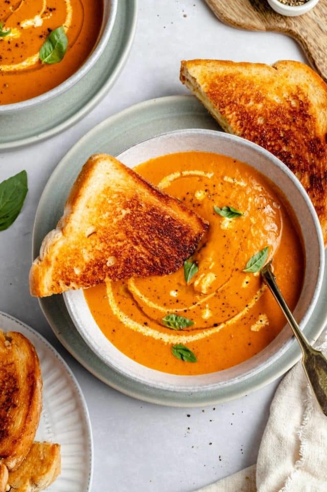 grilled cheese dipped into a bowl of roasted tomato soup