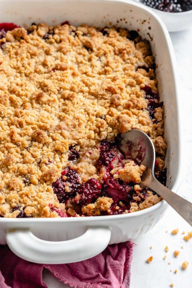 large serving spoon in a blackberry crumble 