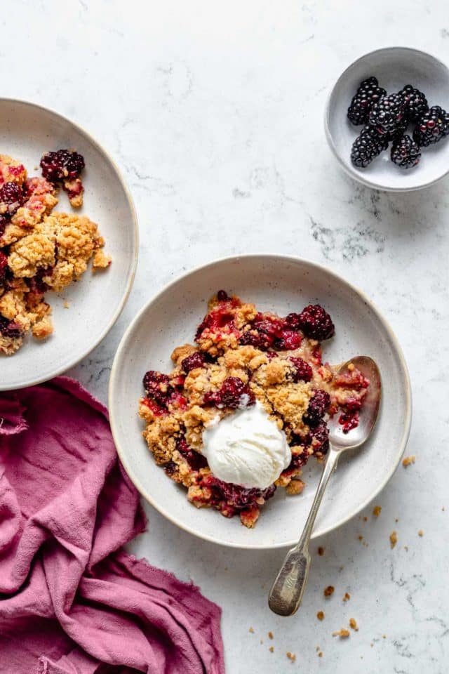 servings of blackberry crumble served on small plates with vanilla ice cream