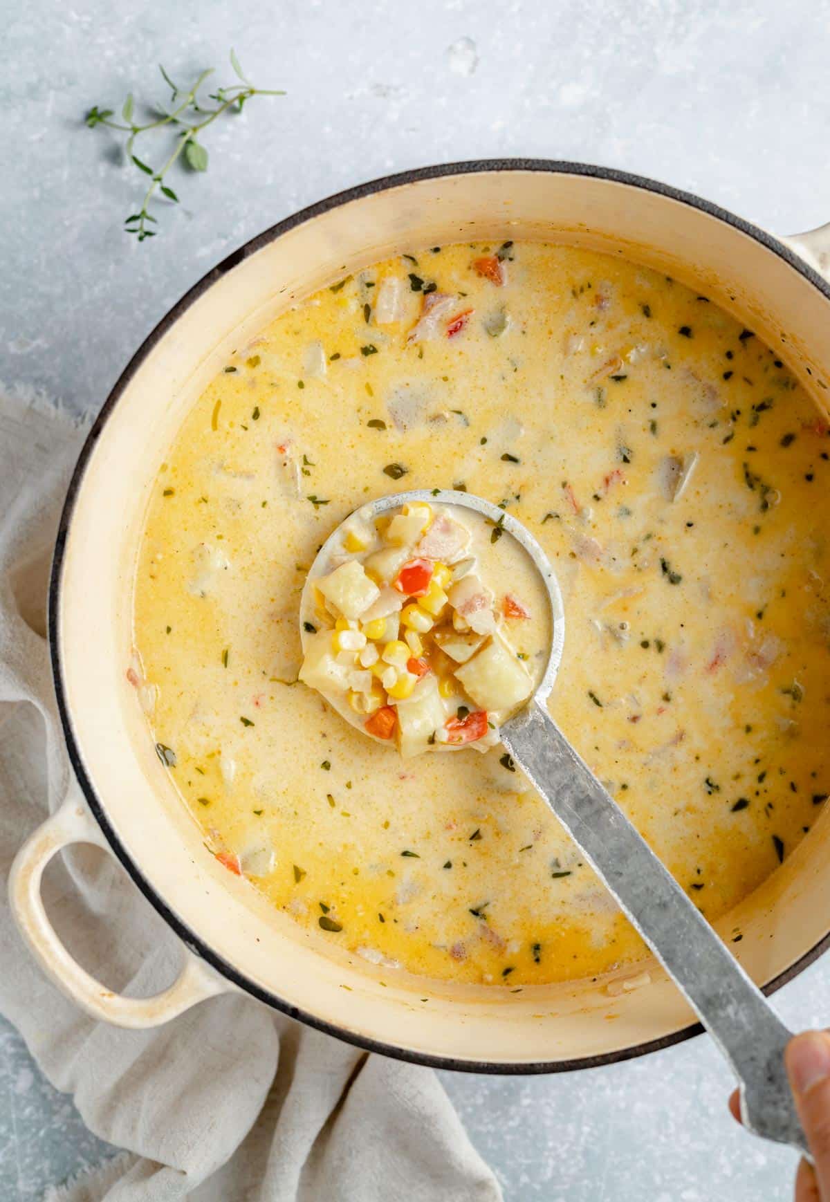 Creamy corn chowder in a large pot with a ladle.