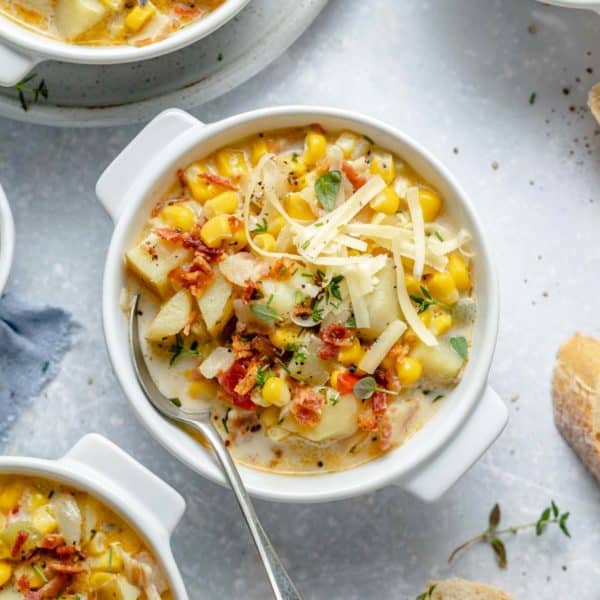 Soup with potatoes and corn in a white bowl.