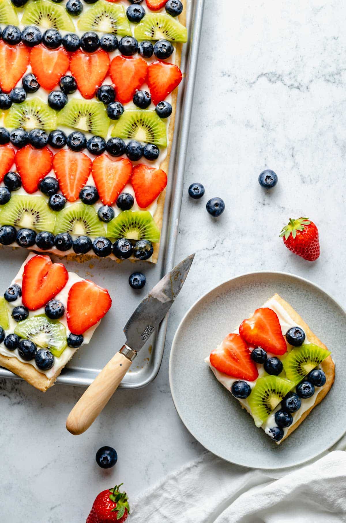 cutting servings of sugar cookie fruit pizza