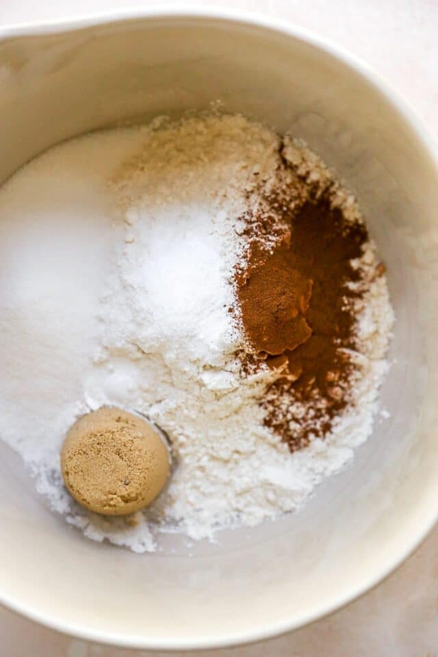 Adding flour, cinnamon, baking powder, and sugar to a large bowl.