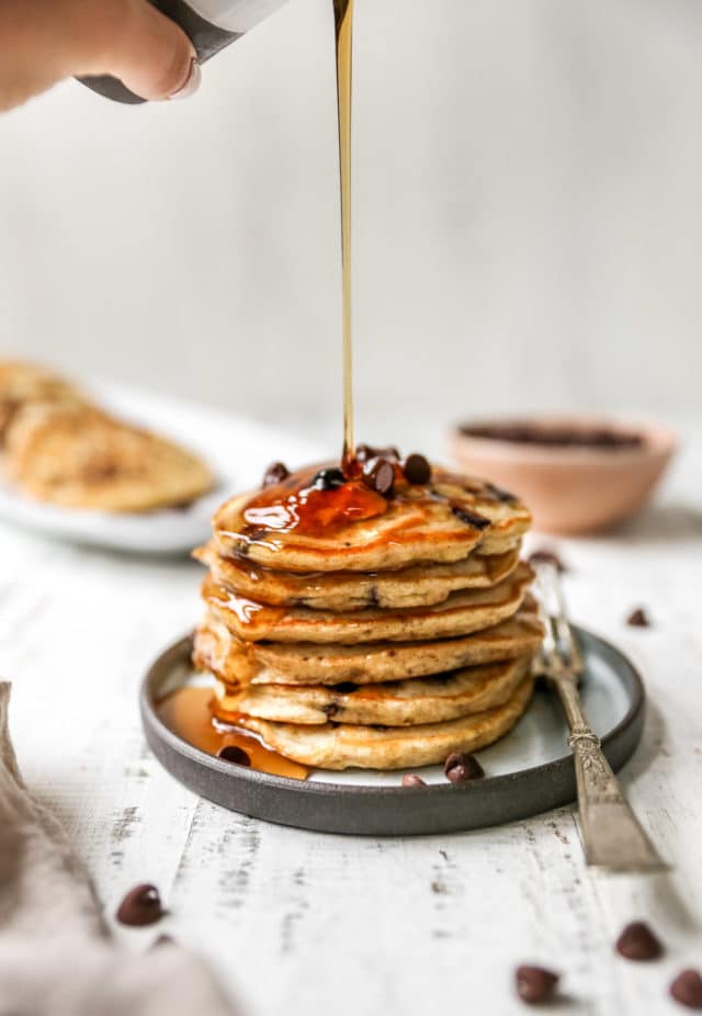 drizzling syrup over chocolate chip pancakes
